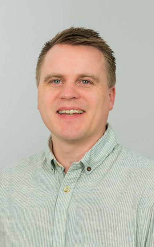 a man wearing glasses and smiling at the camera